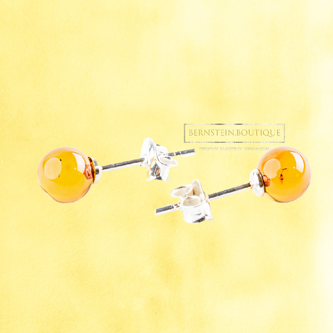 These simple yet striking stud earrings each feature two small, lustrous yellow spheres of natural Nordic amber, mounted on Sterling Silver 925 posts.
The color palette of these transparent amber beads, deriving naturally from the material itself, is particularly ambivalent depending on light exposure: it can beautifully unveil almost the entire spectrum of yellows, from a pale lemon to a deep honey-gold, offering a captivating play of color that continuously unfolds.