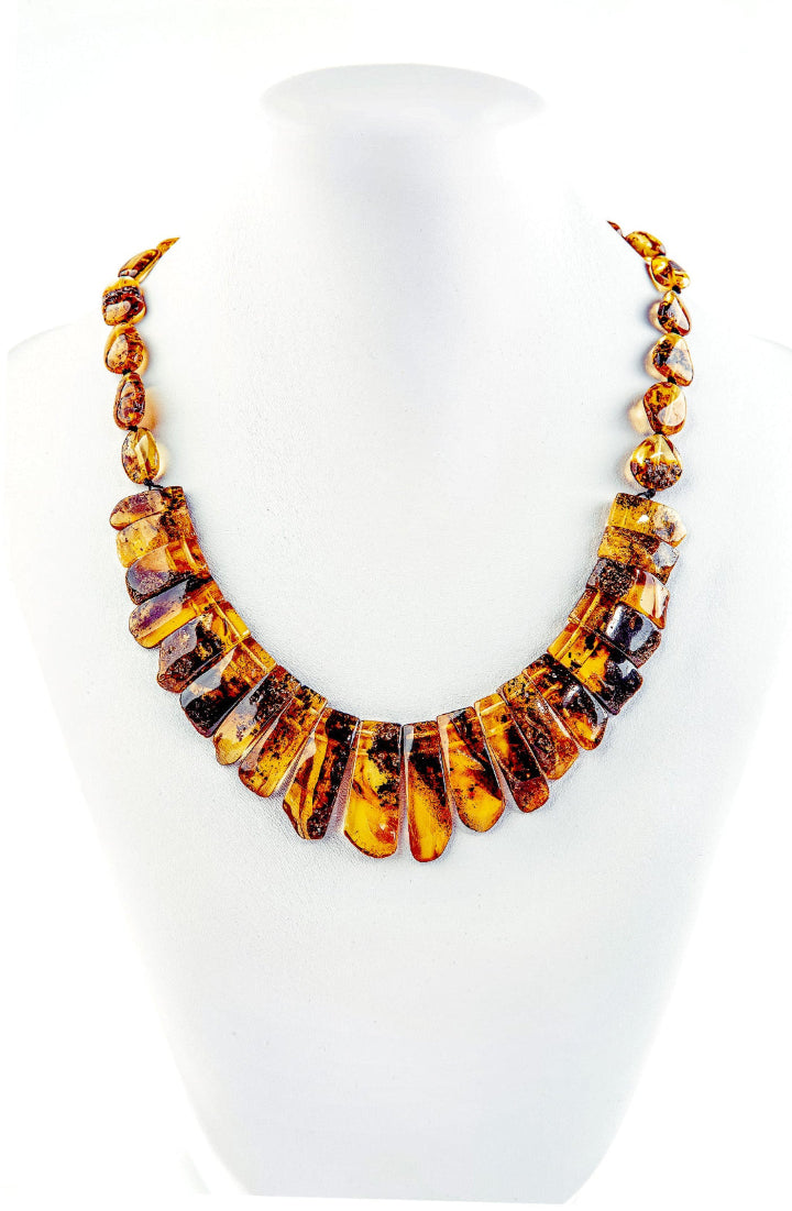 Dieses zeitlose Collier, inspiriert von der antiken griechischen Schmuckkunst, besticht durch seine Länge von 45 cm und sein Gewicht von 22 Gramm. Die einzelnen, hochglanzpolierten zahnigen Bernsteinstücken aus dem Norden variieren in der Größe von 1 bis 3 cm und verleihen dem Schmuckstück eine einzigartige Brillanz und Farbtiefe. Der dezente und langlebige Schraubverschluss aus Kunststoff rundet das elegante Design ab. Ein luxuriöses Accessoire, das jedem Outfit eine stilvolle Note verleiht.