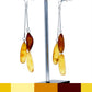 Stud earrings with hanging chains, each with three grain-shaped amber beads