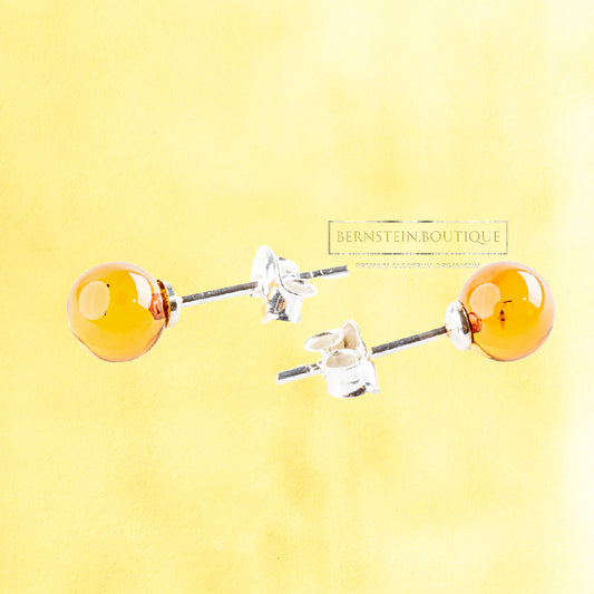 These simple yet striking stud earrings each feature two small, lustrous yellow spheres of natural Nordic amber, mounted on Sterling Silver 925 posts.
The color palette of these transparent amber beads, deriving naturally from the material itself, is particularly ambivalent depending on light exposure: it can beautifully unveil almost the entire spectrum of yellows, from a pale lemon to a deep honey-gold, offering a captivating play of color that continuously unfolds.